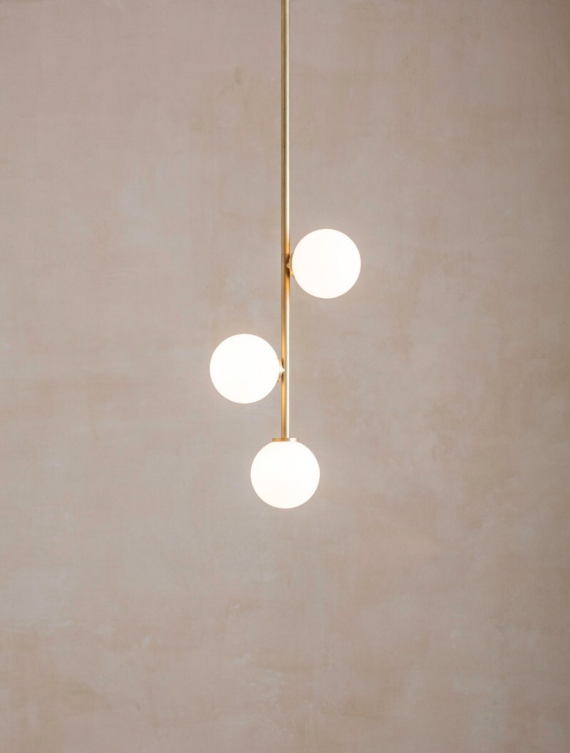 Bloom 3 shown in Stonewashed Brass, and Matte White Globes